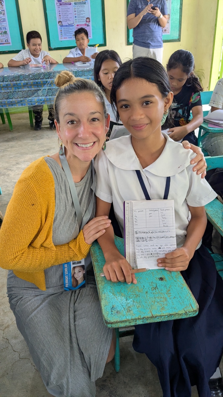 Johna Meldau beside a student holding up her notebook in class.