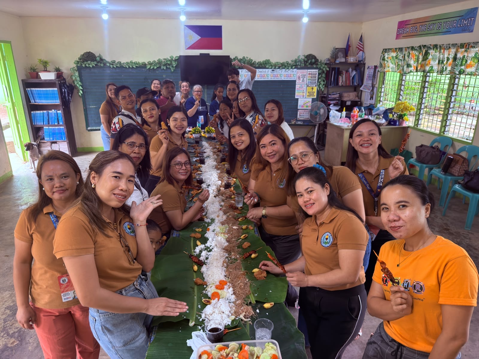 A large group of Filipino teachers gathered around a long banana-leaf feast.