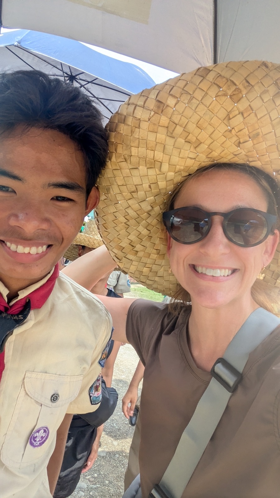 Johna Meldau taking a selfie with a young Filipino scout in a woven hat.