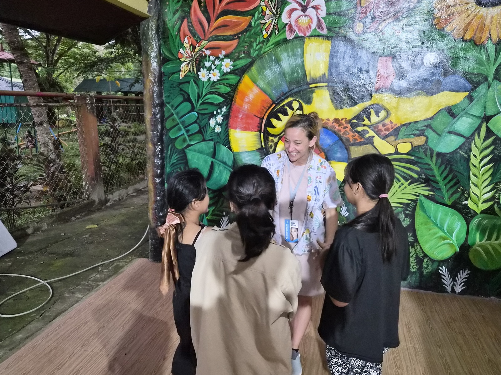 Johna Meldau talking with students in front of a painted mural.